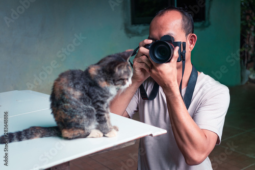 The photographer is shooting a cute cat with a digital camera.