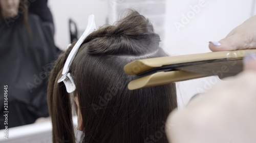 hairdresser makes hair lamination in a beauty salon for a girl with brunette hair. hair care concept.