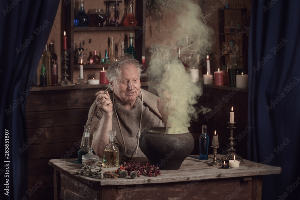 elderly alchemist monk brews  magic potion - obrazy, fototapety, plakaty 