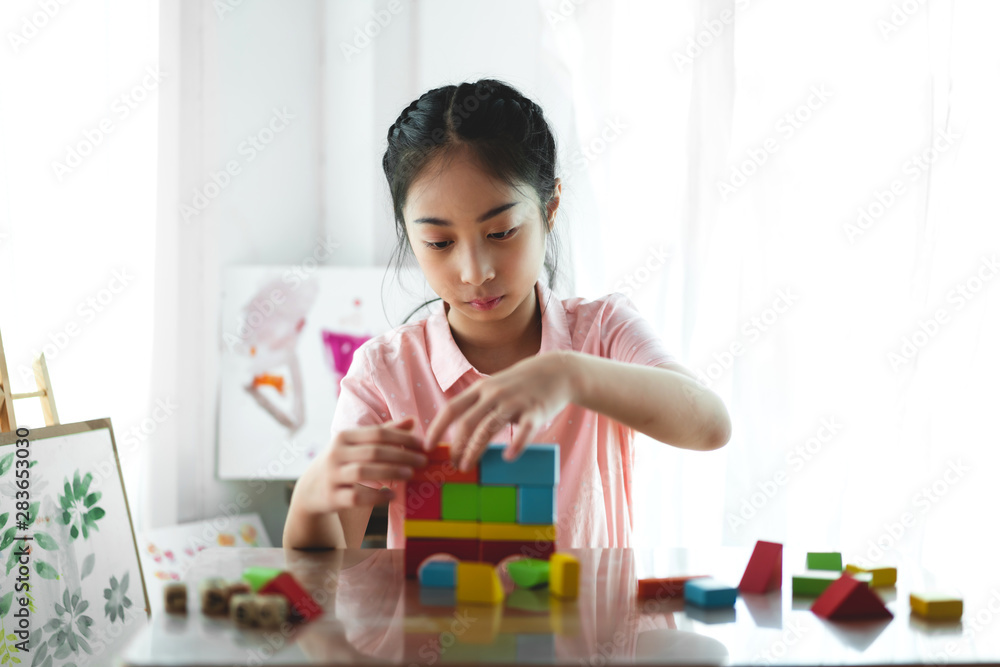 Little cute girl enjoy while playing wooden blocks toys on table at home Little cute girl enjoy while playing wooden blocks toys on table at home