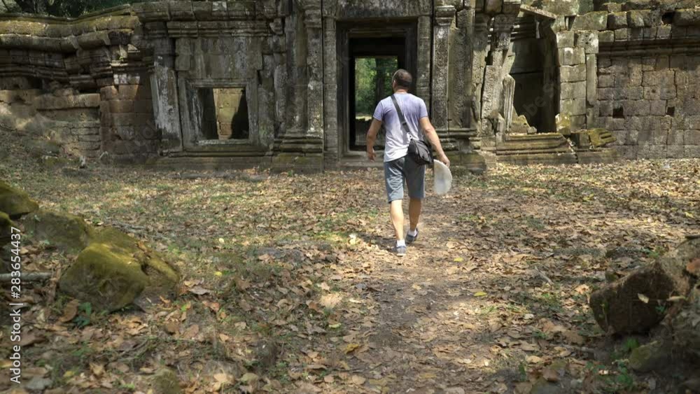 Man sightseeing ancient Angkor Wat temple ruins in Cambodia Man sightseeing ancient Angkor Wat temple ruins in Cambodia
