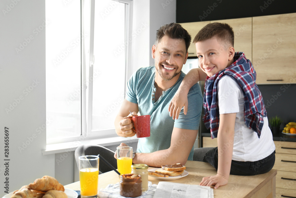 Dad and son having breakfast together in kitchen Dad and son having breakfast together in kitchen