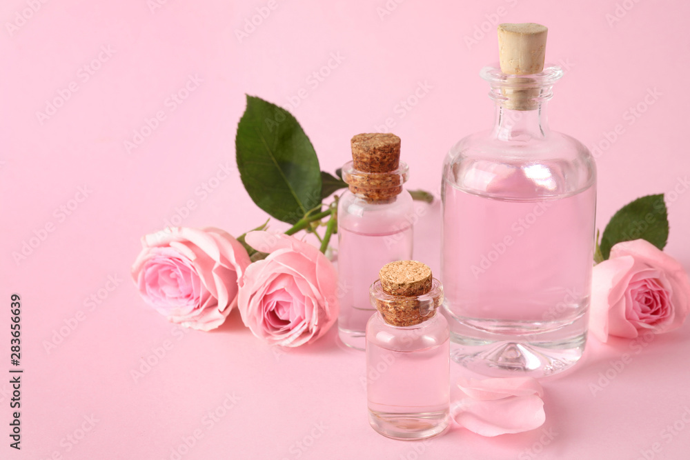Bottles of essential oil and roses on pink background Bottles of essential oil and roses on pink background