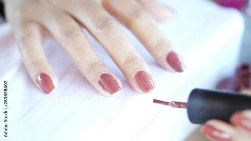 beautiful woman hand applying brown nail polish closeup beautiful woman hand applying brown nail polish closeup