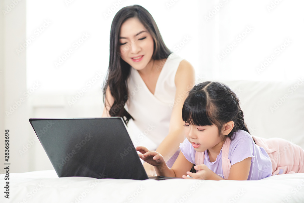 Mother watching her daughter who is learning to use the computer. Mother watching her daughter who is learning to use the computer.