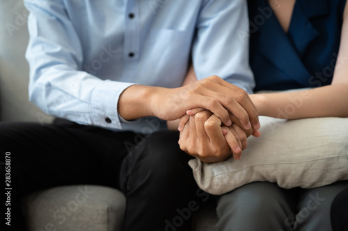 Close-up of Asian couple join hand give to encourage while sitting on the couch in the  room to consult mental health problems by doctor. Health and illness concepts © sorrapongs