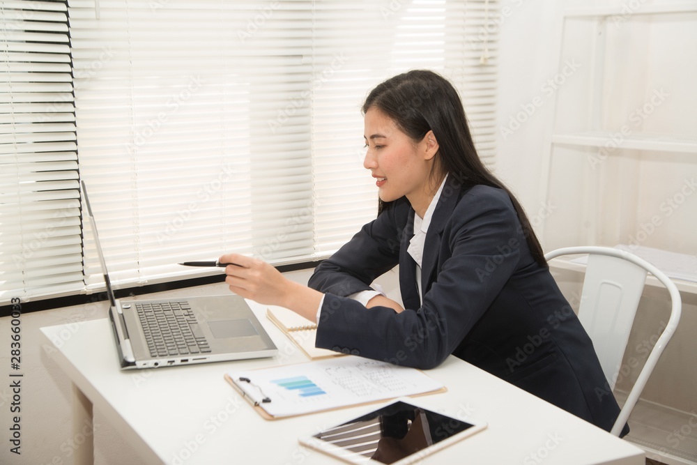 Smiling young Asian businesswoman using laptop at home office workplace.. Smiling young Asian businesswoman using laptop at home office workplace..