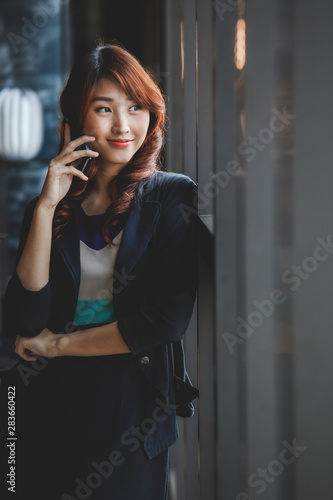 Young attractive asian business woman using mobile phone in  working place. © RooftopStudioBangkok