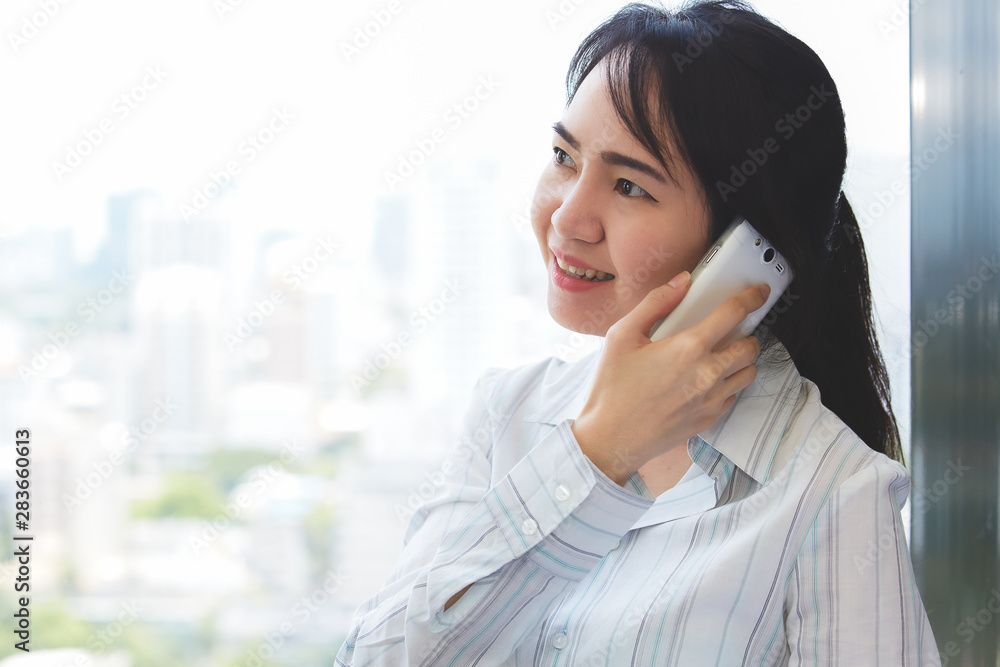 Asian business woman in smile face are using mobile phones and laptops in the office. Asian business woman in smile face are using mobile phones and laptops in the office.
