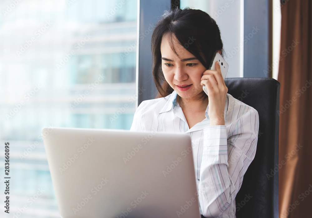 Asian business woman in smile face are using mobile phones and laptops in the office. Asian business woman in smile face are using mobile phones and laptops in the office.