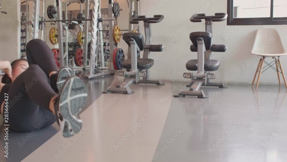 Sport woman doing bicycle crunching sit up on floor in fitness gym. People lifestyles and workout sport training club activity concept. Bodybuilder and weight lifting. Healthy life and wellness health Sport woman doing bicycle crunching sit up on floor in fitness gym. People lifestyles and workout sport training club activity concept. Bodybuilder and weight lifting. Healthy life and wellness health