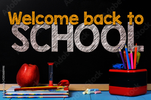 Text welcome back to school on black chalkboard with school accessories