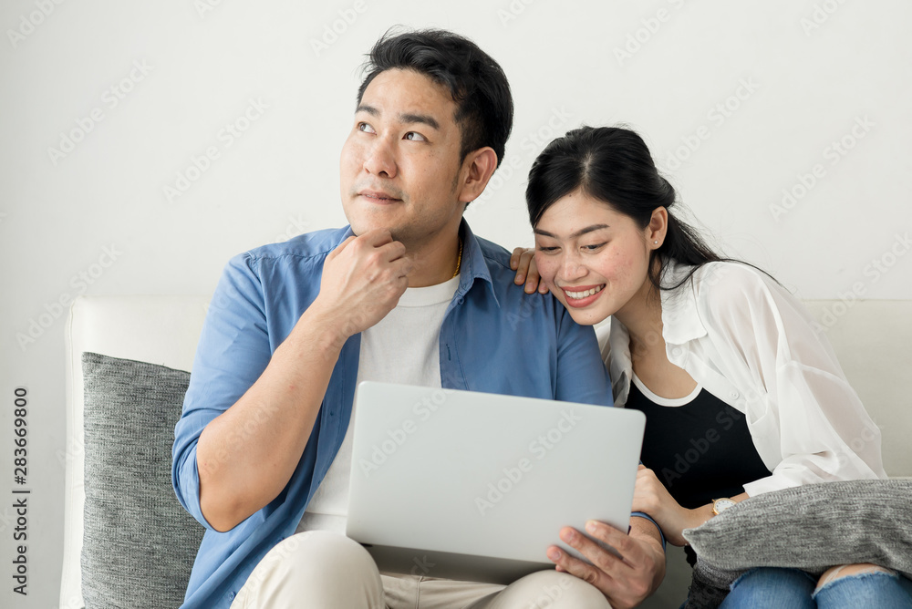 Happy Asian couple shopping online with holding credit card and laptop and sitting at home together, lifestyle concept. Happy Asian couple shopping online with holding credit card and laptop and sitting at home together, lifestyle concept.