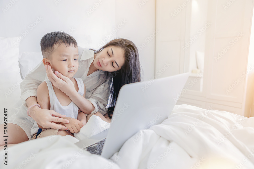 Computer addiction concept. Mother take care her boy because of overuse the laptop computer in the bed room. Computer addiction concept. Mother take care her boy because of overuse the laptop computer in the bed room.