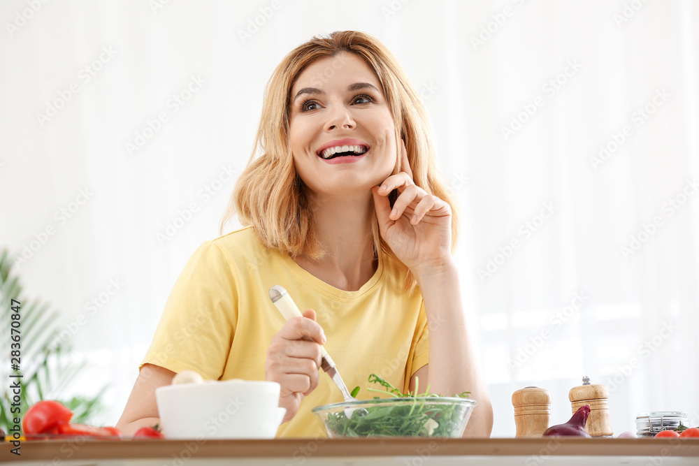 Woman with healthy vegetable salad in kitchen