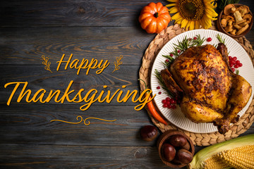 Happy Thanksgiving holiday background. Roasted whole chicken or turkey with autumn vegetables for thanksgiving dinner on wooden background
