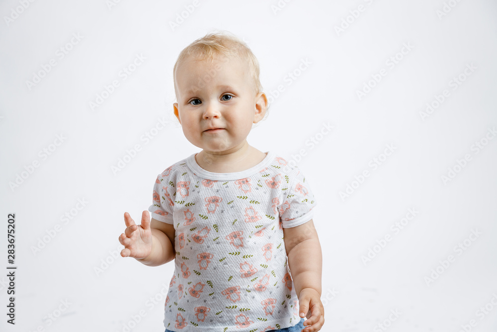 A little cute happy girl rejoices and laughs on her first birthday on a white background. Slapstick with confetti, a balloon filled with helium, a silver cap.