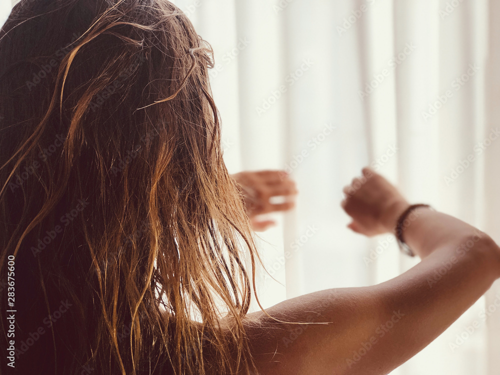 Fototapeta premium Silhouette of a girl while waking up in the room and holding curtain.