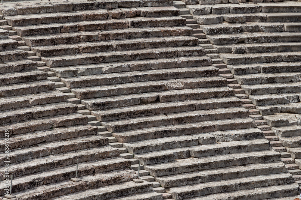 Stairs of the ancient theatre of Epidaurus in the Epidaurus town, on Peloponnesus peninsula, Greece. The theater was dedicated to the ancient Greek God of medicine, Asclepius. Stairs closeup.