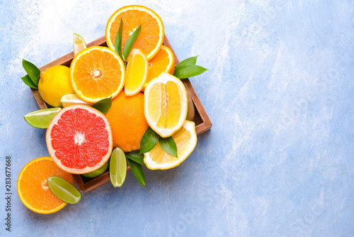 Box with different citrus fruits on color background © Pixel-Shot