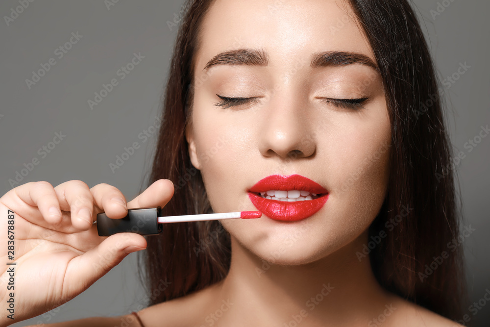 Beautiful young woman with bright lipstick on grey background Beautiful young woman with bright lipstick on grey background