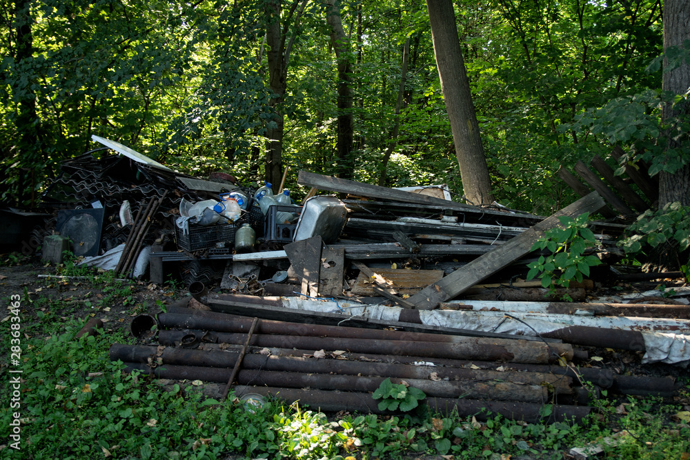 Inefficient waste from metal pipes, wooden boards, plastic bottles dumped in the forest Inefficient waste from metal pipes, wooden boards, plastic bottles dumped in the forest