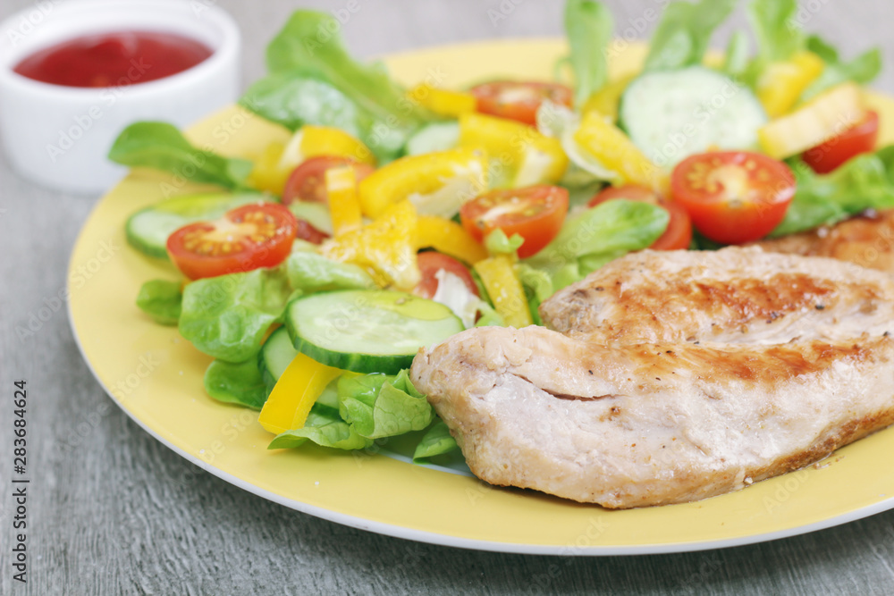 Grilled chicken breast with raw vegetables salad