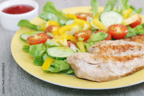 Grilled chicken breast with raw vegetables salad