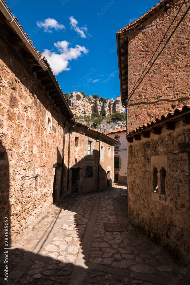 lonely streets on a sunny day of beautiful little town Orbaneja del Castillo in Burgos, Spain, with old stone houses
