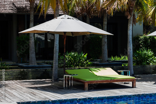 Outdoor tables and green sun beds or sun loungers beside the pool