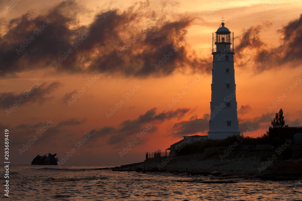 Lighthouse and shipwreck at Cape Tarkhankut, Crimea in the last rays of the sun