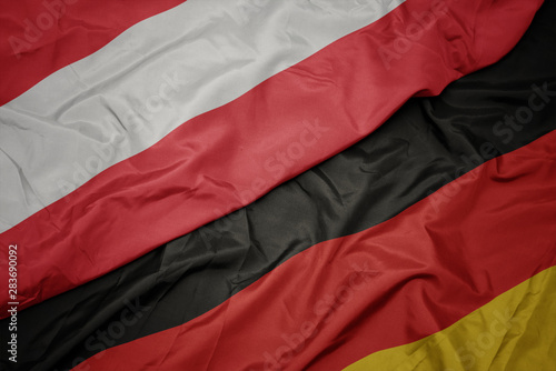 waving colorful flag of germany and national flag of austria.