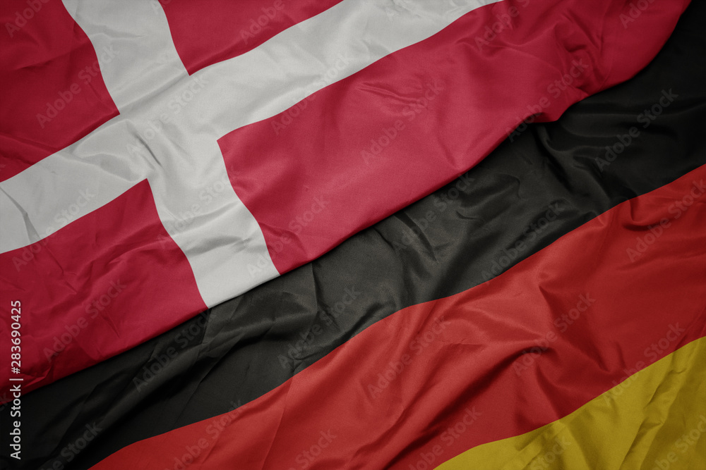 waving colorful flag of germany and national flag of denmark.