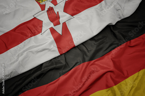 waving colorful flag of germany and national flag of northern ireland.