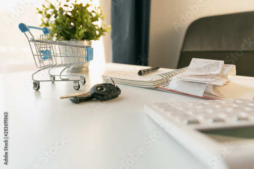 Car purchase concept. Empty shopping cart , car keys, calculator and notebook on white table