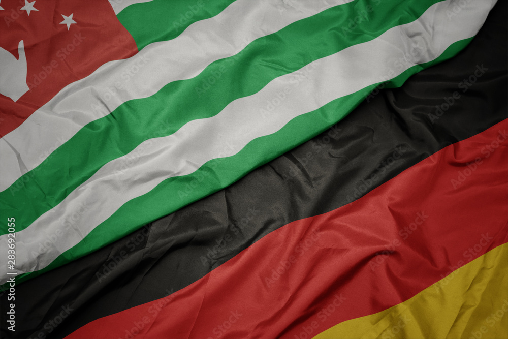 waving colorful flag of germany and national flag of abkhazia.