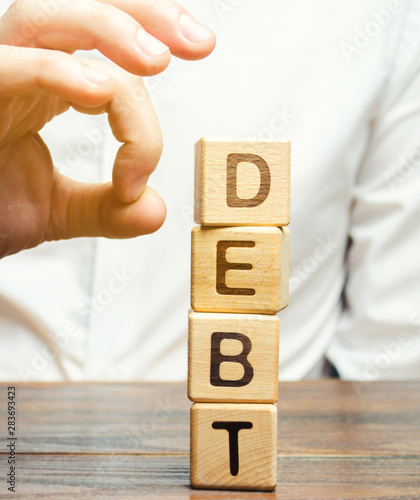 Businessman removes wooden blocks with the word Debt. Reduction or restructuring of debt. Bankruptcy announcement. Refusal to pay debts or loans and invalidate them. Debts service relief