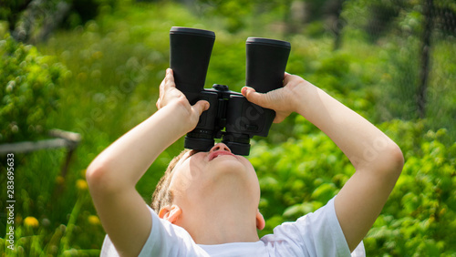 curious little boy looking trough a binoculars