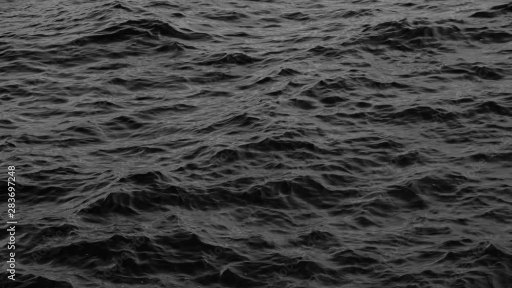 Dark slow motion black and white rippling sea surface background Dark slow motion black and white rippling sea surface background