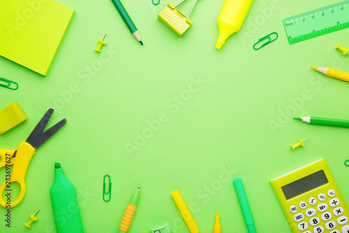 Green school accessories on light green background. Back to school concept, minimalism