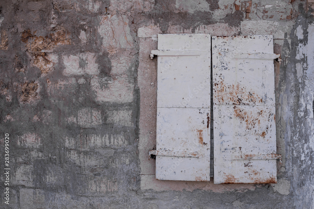 Stone wall and a window with closed shutter