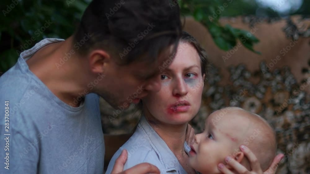 Close portrait of a husband and a wife beaten by him with a small child in her arms. A man yells at his wife and child. Domestic violence, abuser and its victims Close portrait of a husband and a wife beaten by him with a small child in her arms. A man yells at his wife and child. Domestic violence, abuser and its victims