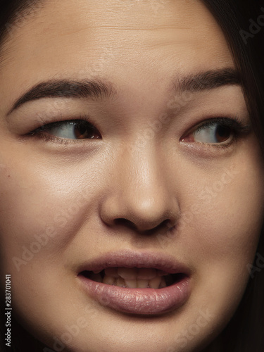 Close up portrait of young and emotional chinese woman. Highly detail photoshot of female model with well-kept skin and bright facial expression. Concept of human emotions. Clumsiness, looking at side © master1305