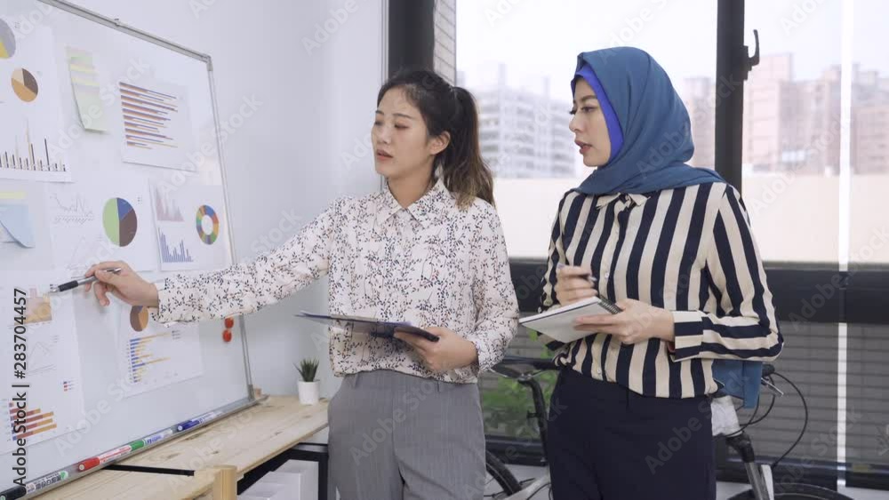 manager presents new project plan to malay woman colleague at meeting