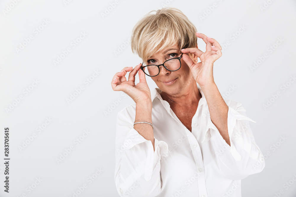 Portrait of alluring adult woman holding eyeglasses and looking at camera
