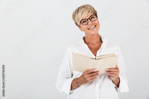 Portrait of joyous middle-aged woman wearing eyeglasses reading book