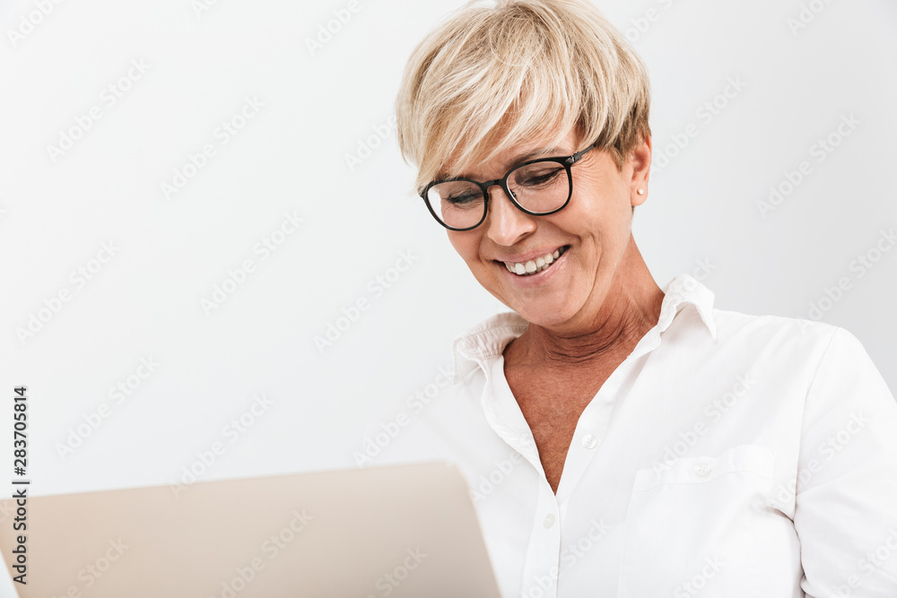 Image closeup of happy adult woman wearing eyeglasses smiling while using laptop computer Image closeup of happy adult woman wearing eyeglasses smiling while using laptop computer