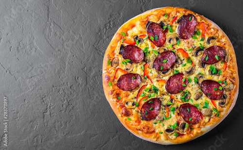 Pepperoni Pizza with Mozzarella cheese, salami, pepper, Spices and mushrooms. Italian pizza on Dark grey black slate background