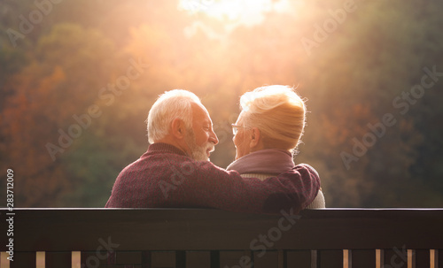 Senior couple sitting on bench in autumn park photo