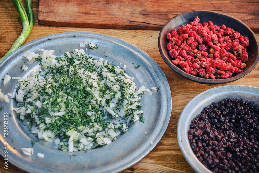 Life of the first American settlers in the wild West and gold miners. Berries, greens and onion salad on a wooden Board, close-up Life of the first American settlers in the wild West and gold miners. Berries, greens and onion salad on a wooden Board, close-up